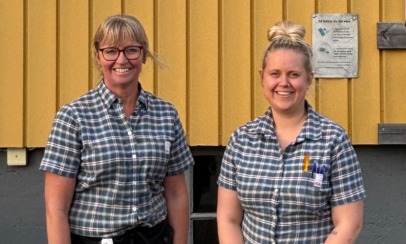  Two of the women who work stand outside the shop with its yellow facade.