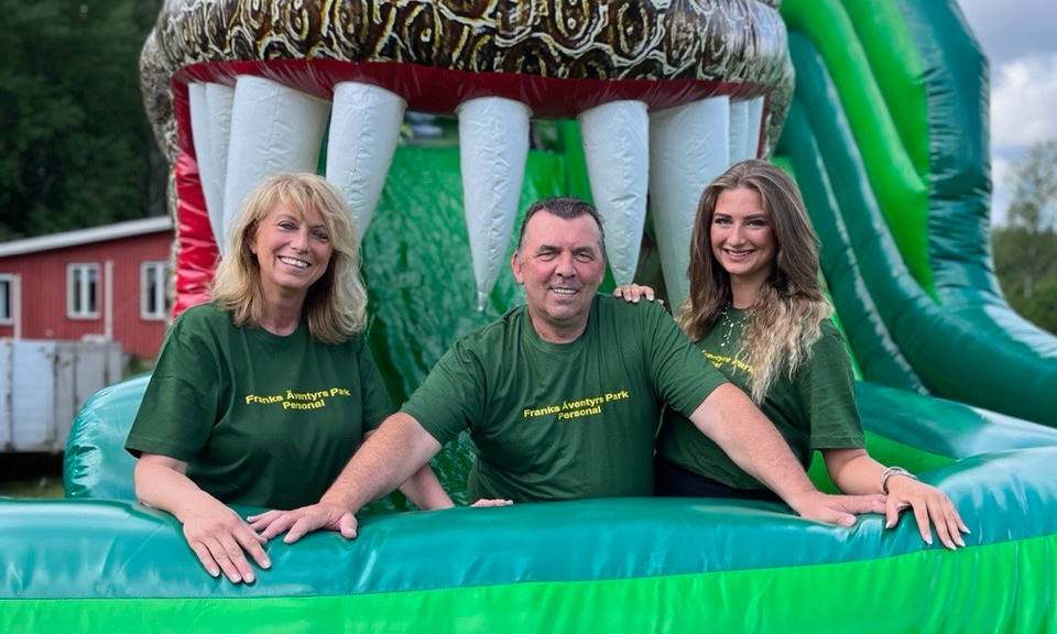  The two women and the man driving Franks Äventyrspark i Älvsered are standing in a green bouncy castle representing a dinosaur.